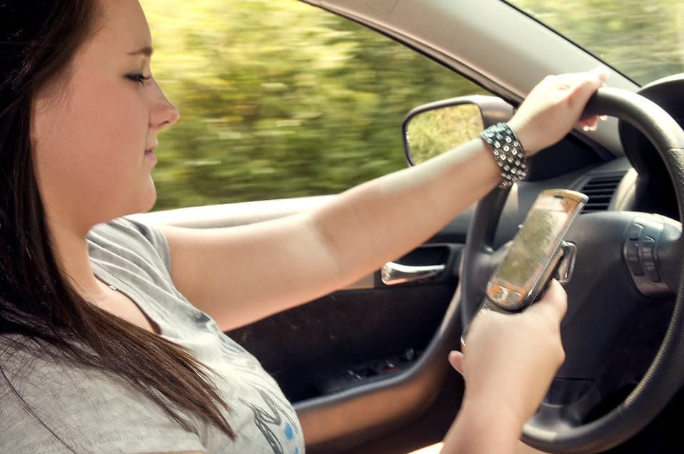 A teen texts while driving in this stock image licensed for non-commercial reuse.